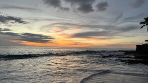 Ein Strand mit Wellen und einem Sonnenuntergang.