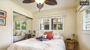 Ein Schlafzimmer mit einem Bett, einem Nachttisch, einem Spiegel und einem Fenster mit Fensterläden.