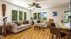 A spacious living room with a wooden floor, two sofas, a coffee table, and a dining area with a table and chairs.