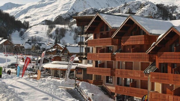 A ski resort with wooden buildings, ski lifts, and snow-covered mountains in the background. - 100m from resort center, 1st floor, balcony, parking, tv, ski locker, 20m², Valloire (Valloire)