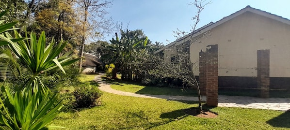 A house with a paved driveway, a brick pillar, and a well-maintained lawn.