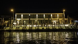 Hotel à beira-mar com uma fileira de espreguiçadeiras e guarda-sóis ao longo da orla.
