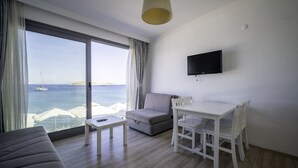 Quarto moderno com uma janela grande, um sofá, uma mesa e uma televisão.