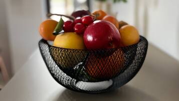A black wire basket containing various fruits on a table.