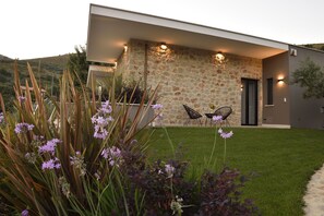 A modern house with a stone facade, a well-maintained lawn, and outdoor seating.