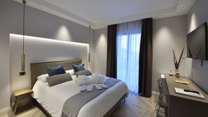 Quarto de hotel moderno com uma cama grande, mesas de cabeceira, escrivaninha e televisão.
