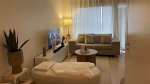 Una sala moderna con un sofá, una mesa de centro, un televisor y una planta.