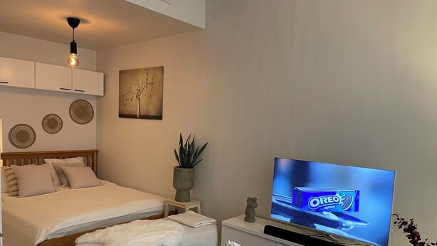 Un dormitorio moderno con una cama, televisión, una mesita y objetos decorativos.