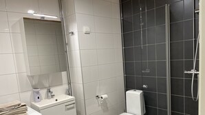 Un baño con lavadora, inodoro y zona de ducha.