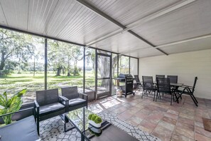 Un patio couvert avec des meubles d’extérieur, un barbecue et une vue sur une pelouse.
