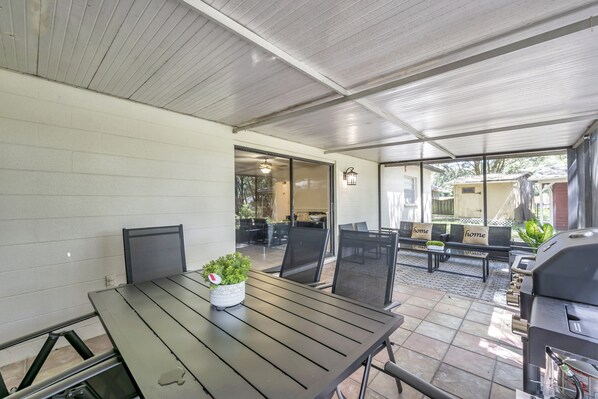 An outdoor patio area with a table, chairs, a grill, and a seating area with benches.