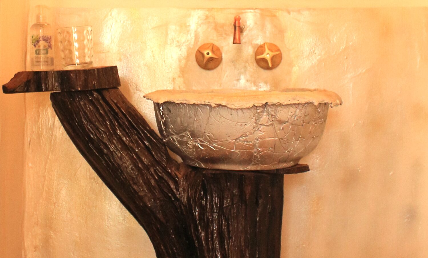 A bathroom with a unique sink design integrated into a tree-like structure.