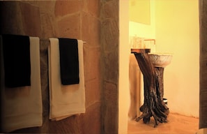 Bathroom features a stone wall and a unique, curved sink.
