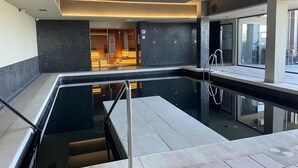 En moderne hotellobby med en pool med glasbund, en trappe og et reception område med en træreception.