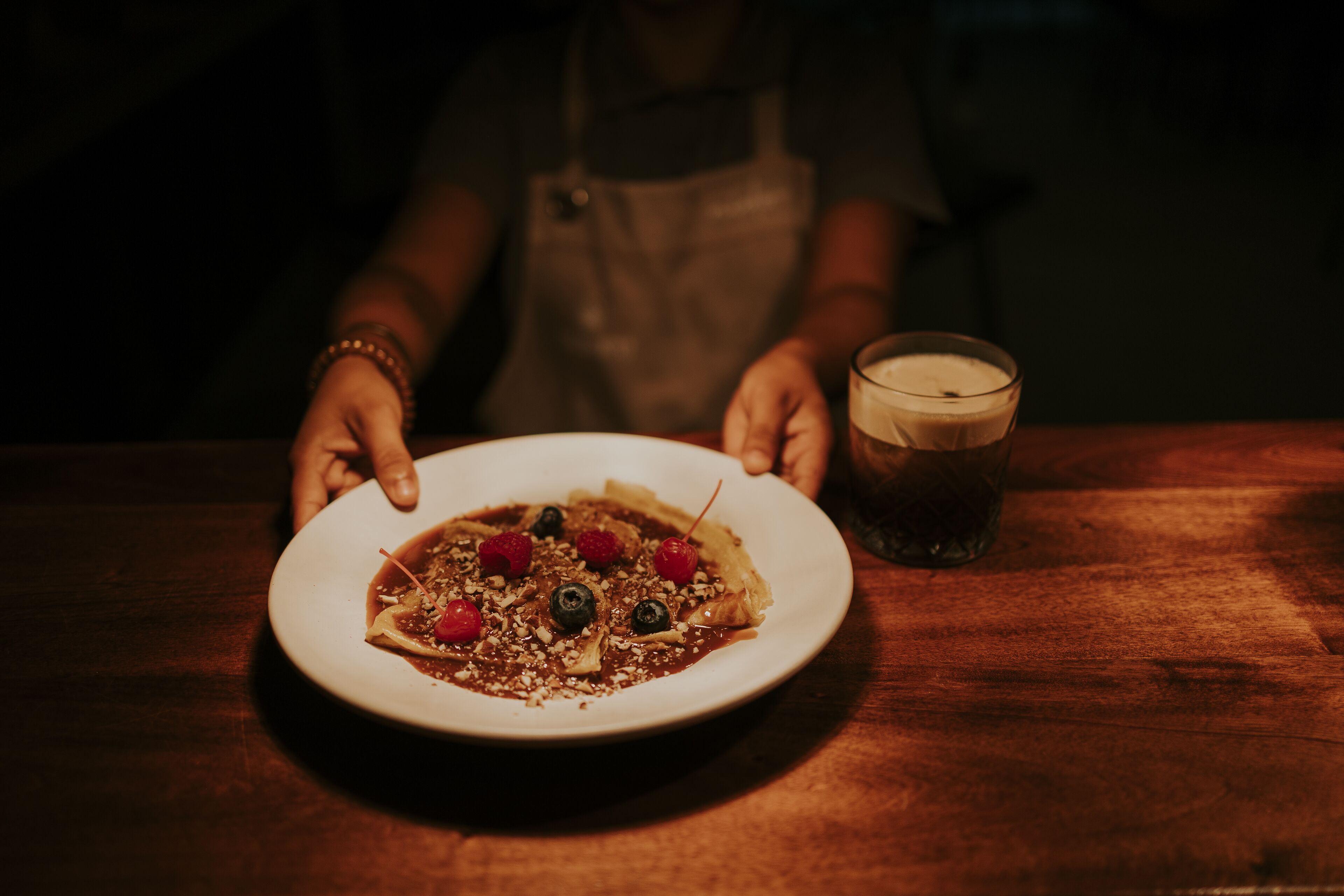 A plate of food on a table with a glass of a dark beverage beside it.