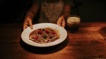 A plate of food on a table with a glass of a dark beverage beside it.