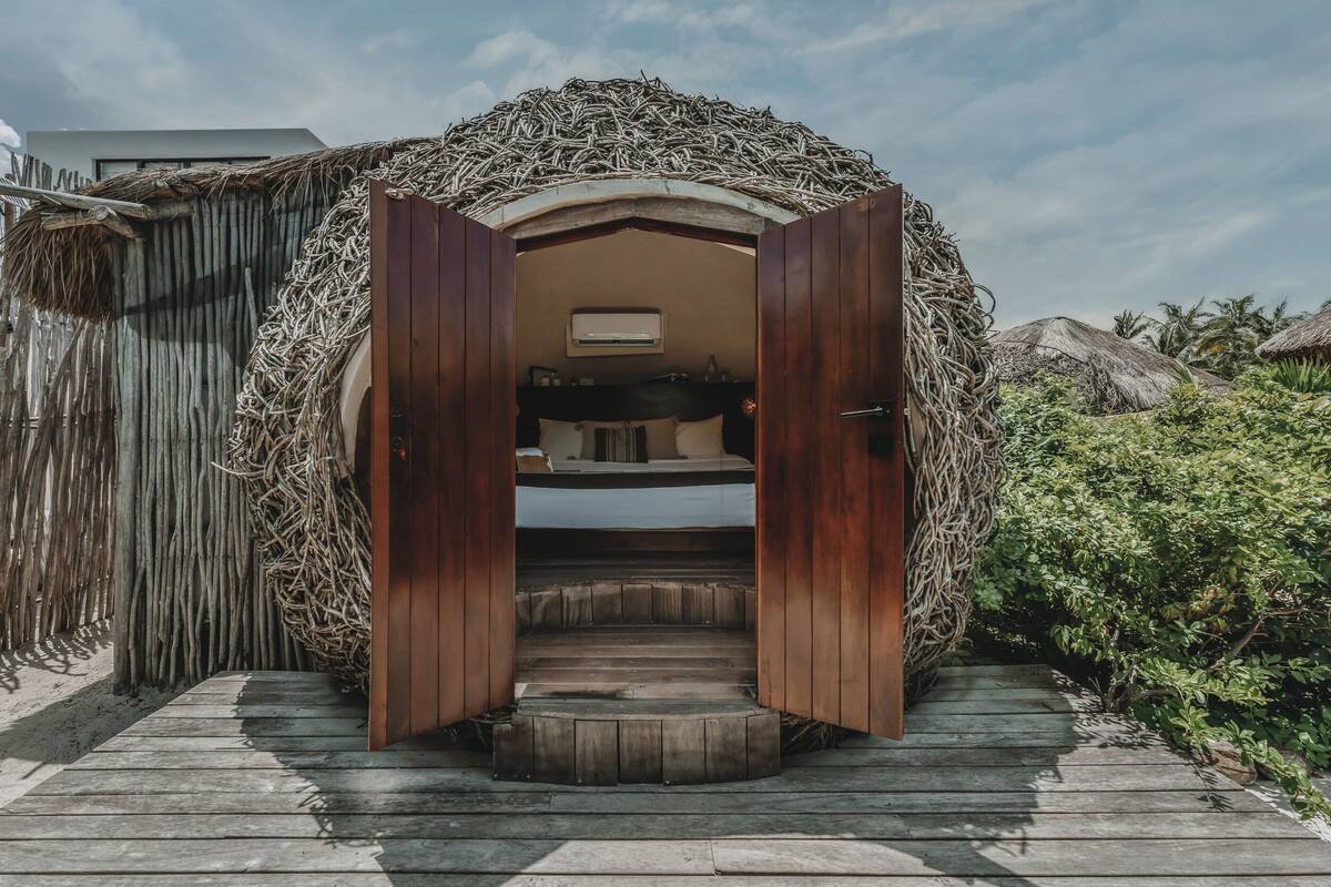 A wooden staircase leading to a room with a bed and an air conditioning unit.