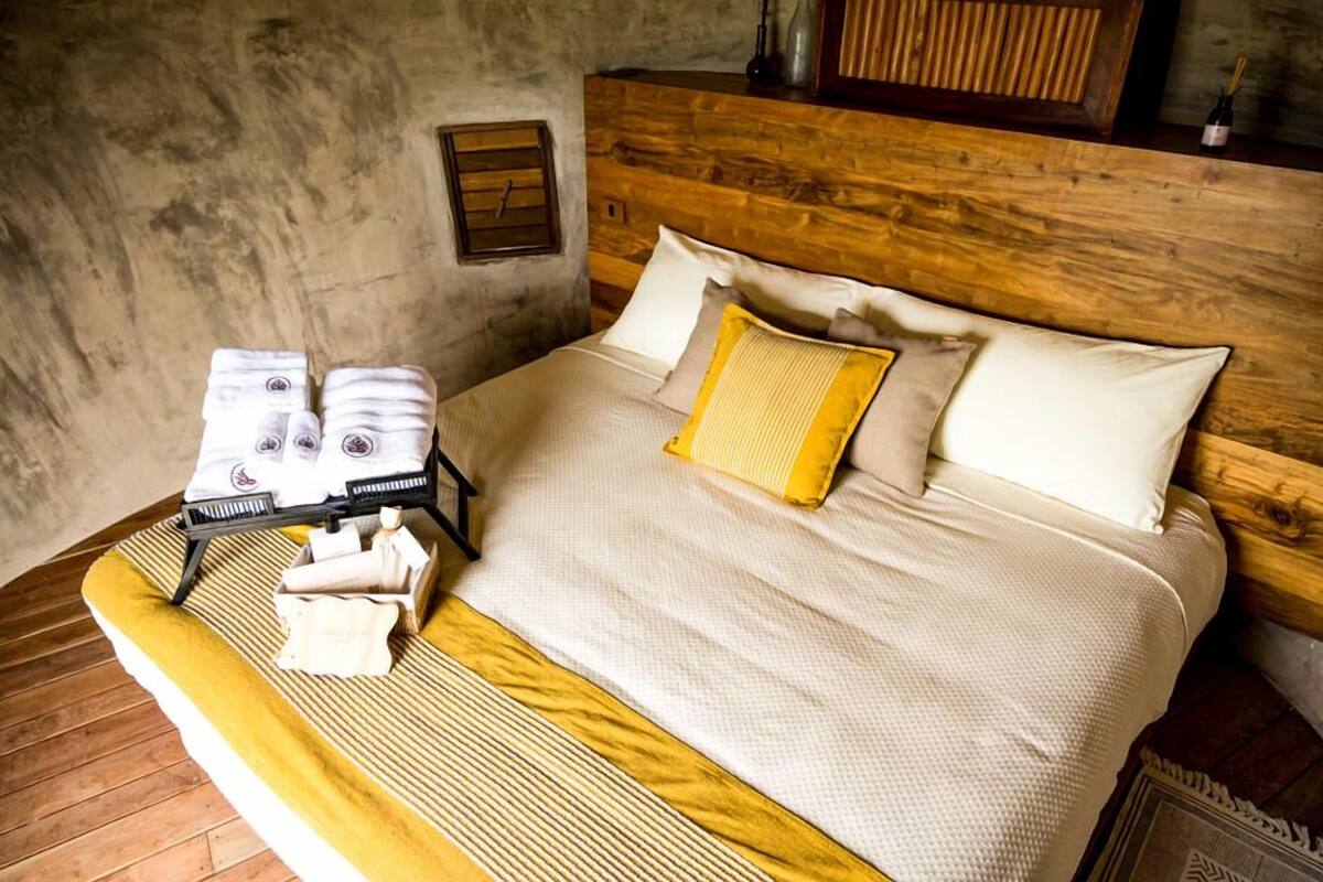 A bed with a wooden headboard, a yellow striped bedspread, and two pillows.