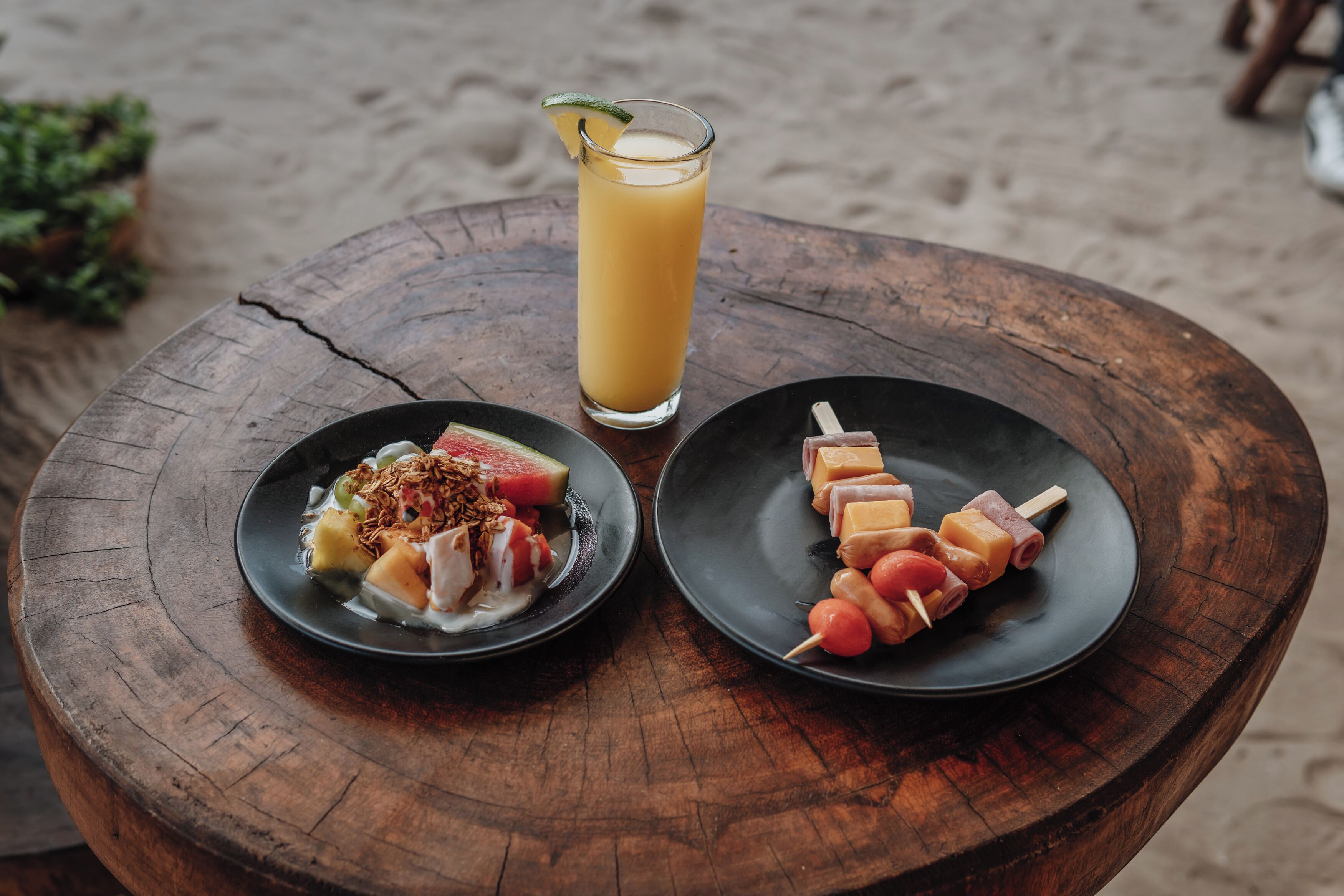 A wooden table with two plates of food and a glass of orange juice.