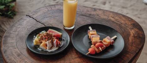 A wooden table with two plates of food and a glass of orange juice.