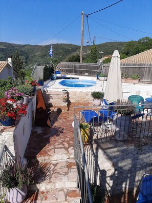 A rooftop terrace with a swimming pool, potted plants, outdoor furniture, and a view of the surrounding hills. - Lefkas Kavalos Atmospheric Villa Kavalina (Lefkada)