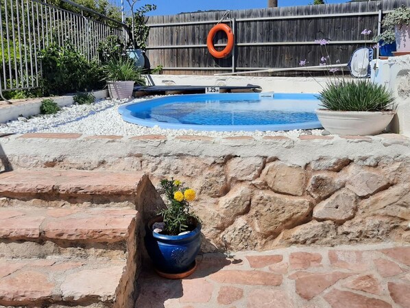 A backyard with a swimming pool, a wooden fence, and a lifebuoy.