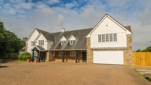 Une maison à deux étages avec un garage, une allée et une clôture en bois.