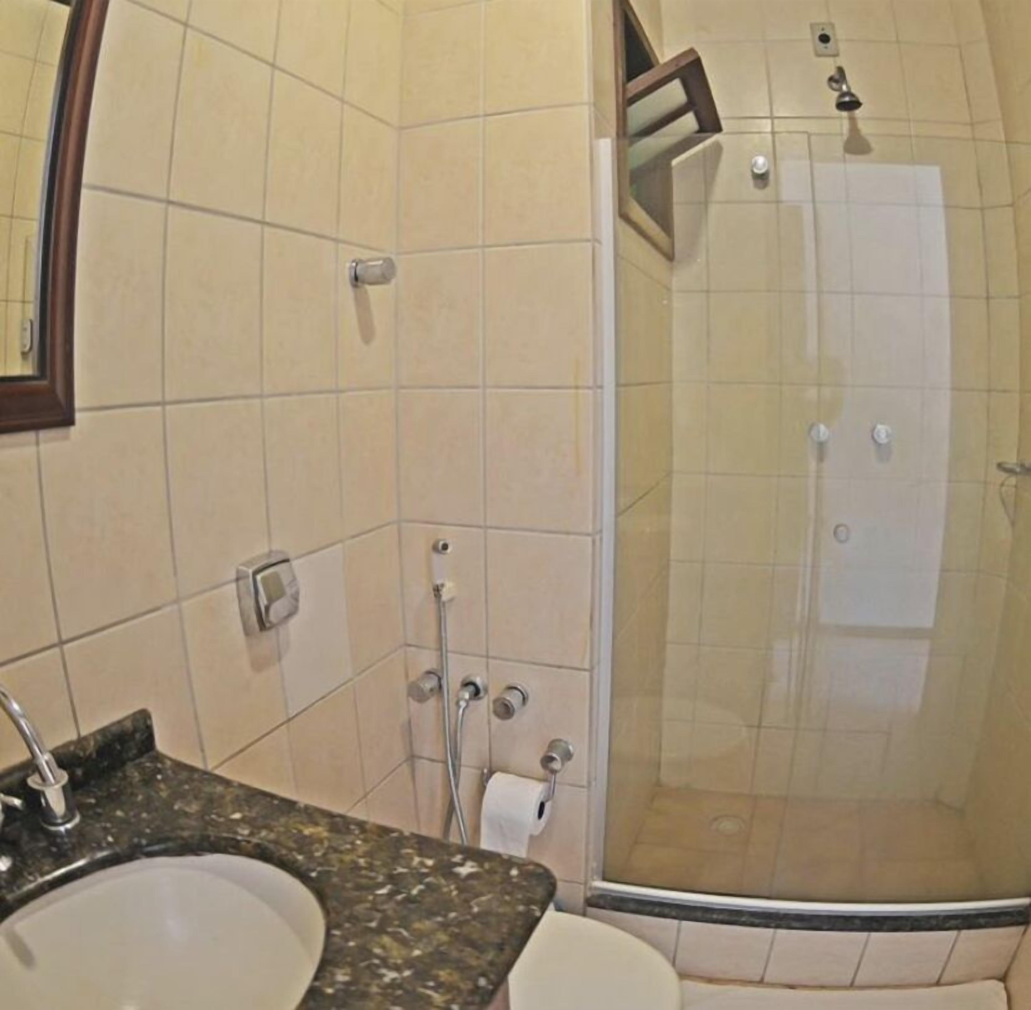 Ein Badezimmer mit Waschbecken, Spiegel, Dusche und Toilette.