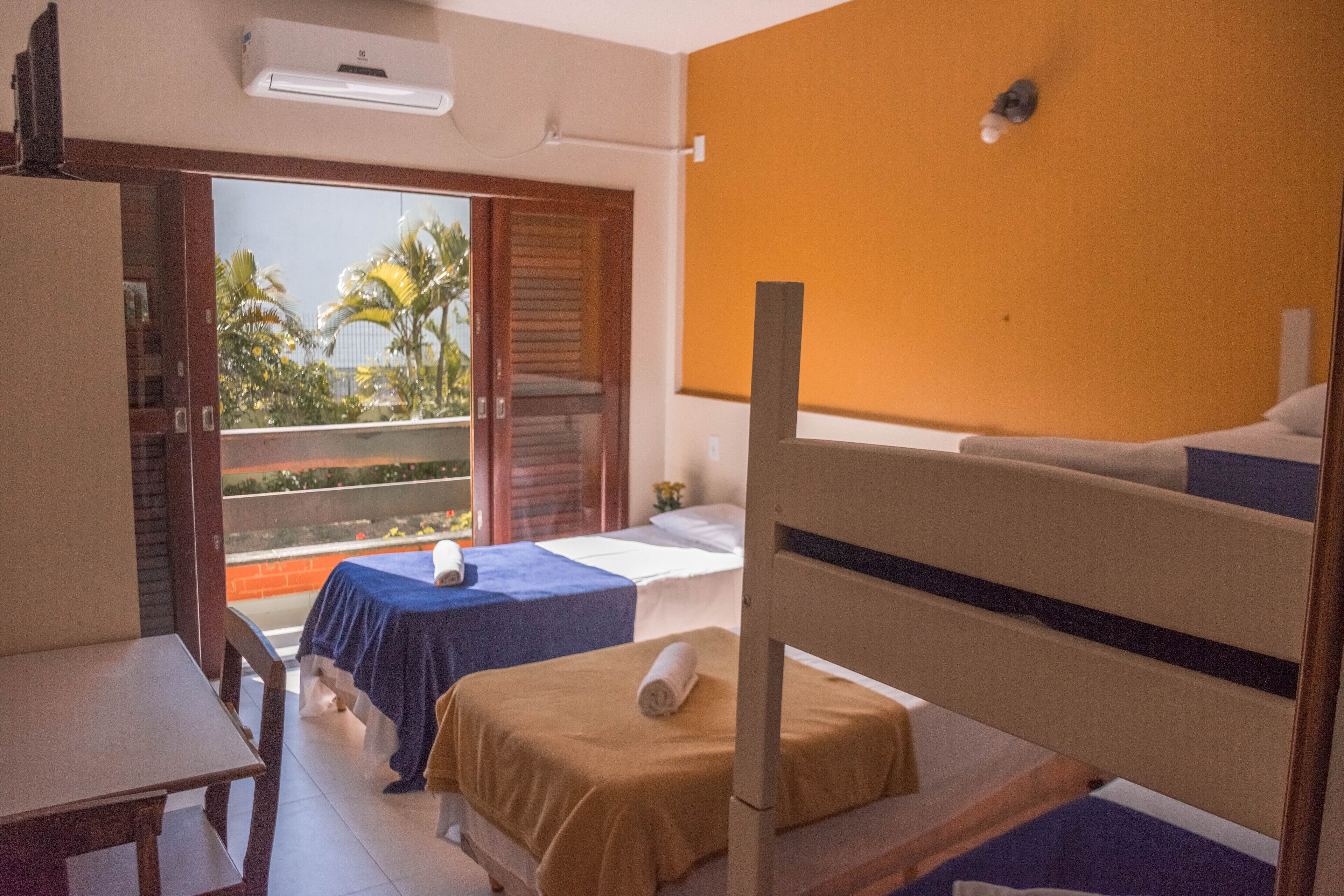A hotel room with a balcony, a bed, a table, and a chair.