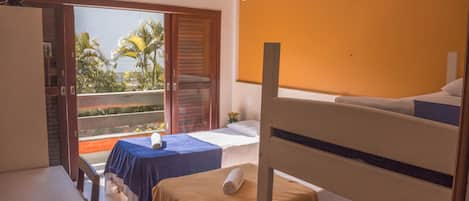 A hotel room with a balcony, a bed, a table, and a chair.