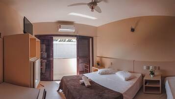 Une chambre d’hôtel équipée d’un lit, d’un bureau, d’une chaise, d’un ventilateur de plafond et d’une fenêtre.