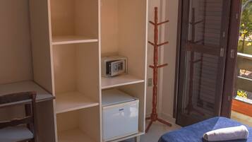 Habitación de hotel con dos camas, un televisor en un estante, un refrigerador pequeño y un perchero.