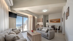 A modern living room with a sofa, coffee table, and a dining area with a table and chairs. - Sunset view villa in plakias,sea view,Private pool (Plakias)