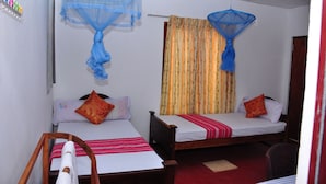 A room with two beds, each with a mosquito net and a red and white striped blanket. - Pawansa Homestay (Habarana)