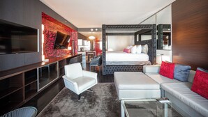 Moderni hotellihuone, jossa on suuri sänky, sohva, televisio ja työpöytä.