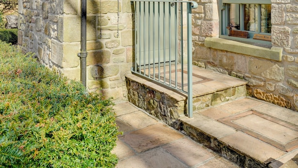 A stone building with a small entrance, a window with a nameplate, and a chimney. - South Stable: Cosy Stone Retreat with Parking (Alnmouth)