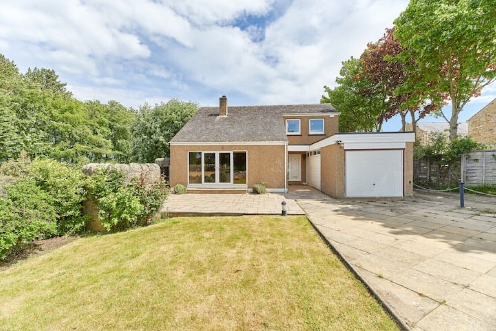 A two-story house with a garage, a paved driveway, and a well-maintained lawn.