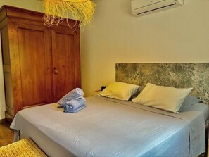 Una camera da letto con un letto, un'armadietto in legno e una lampada a sospensione.