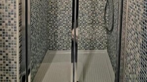 A glass-enclosed shower stall with mosaic tile walls and a metal frame. - Caesar Room (Roma)