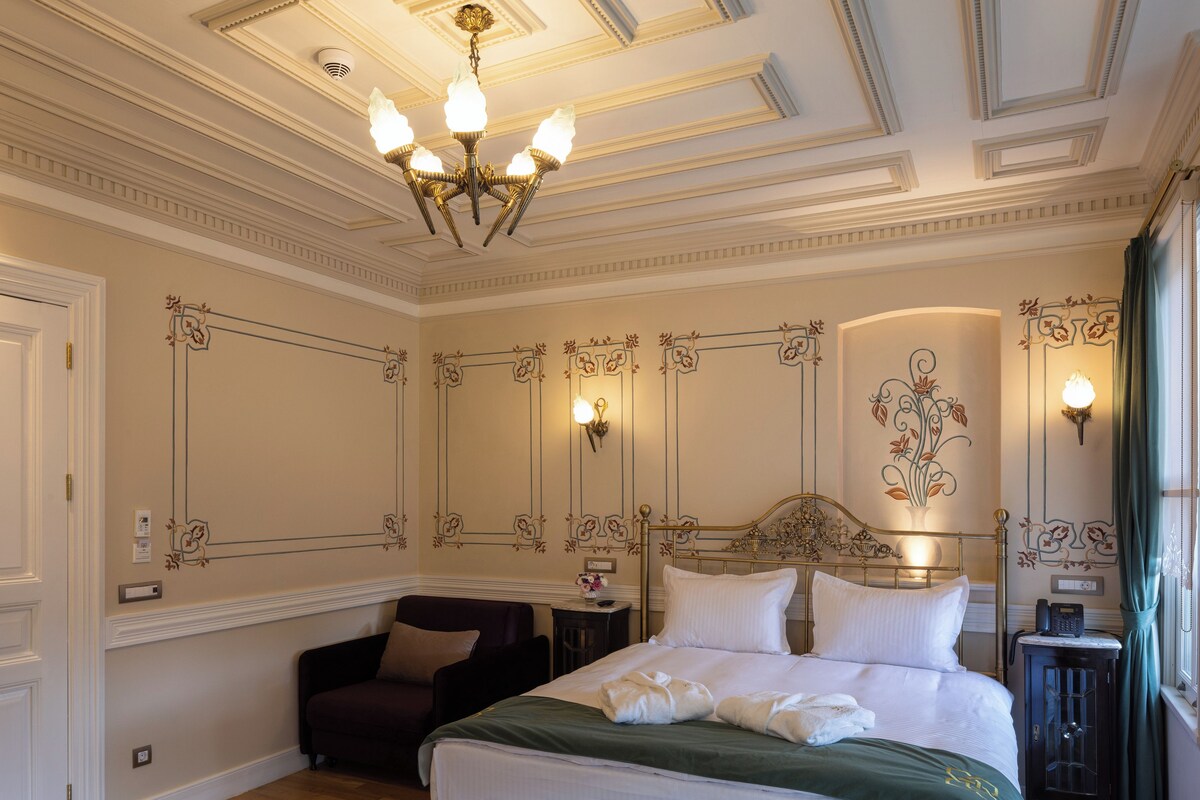 Une chambre à coucher avec un grand lit, un lustre, une table de chevet avec une lampe et un tapis à motifs.
