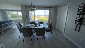 A modern dining area with a glass table, four chairs, and a chandelier. - Beachfront House with Beautiful Ocean Views and Private Beach Access (Melbourne Beach)