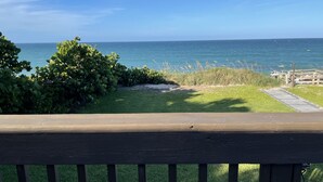 A wooden deck with a view of the ocean and a grassy area with bushes. - Beachfront House with Beautiful Ocean Views and Private Beach Access (Melbourne Beach)