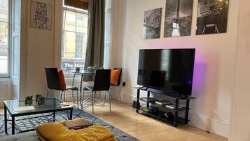 A modern living room with a sofa, TV, and dining area.
