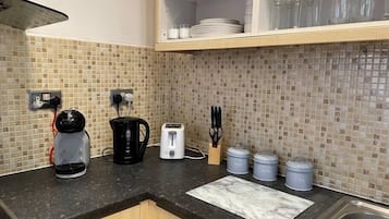 A kitchen with a black countertop, a coffee maker, a toaster, and storage containers.