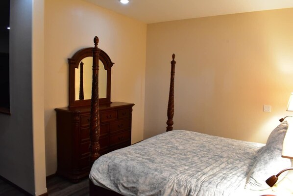 Une chambre à coucher avec un lit, une commode en bois et un miroir.