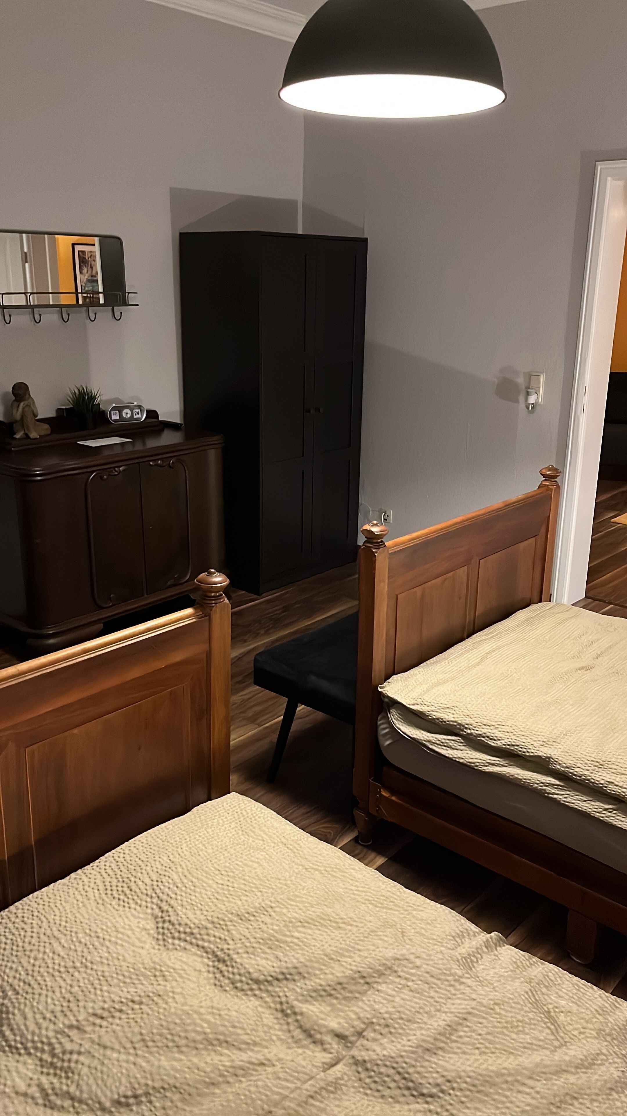 A bedroom with a bed, a nightstand, a dresser, a mirror, and a wardrobe.