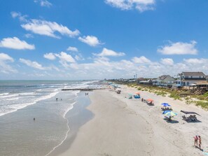 Relax on the beach with comfortable sun loungers and umbrellas, surrounded by residential buildings and the soothing ocean.