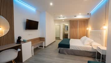 Una habitación de hotel moderna con cama, escritorio, silla, televisión y vestidor.