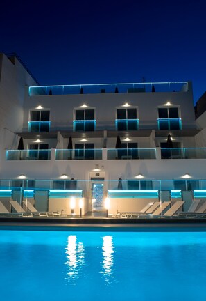 Una piscina al aire libre, sombrillas, sillones reclinables de piscina