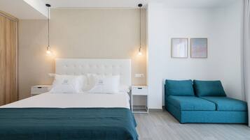 A modern bedroom with a large bed, a nightstand, a blue sofa, and two wall-mounted lights.
